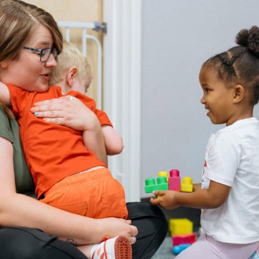 Woman hugging child wearing an orange shirt.