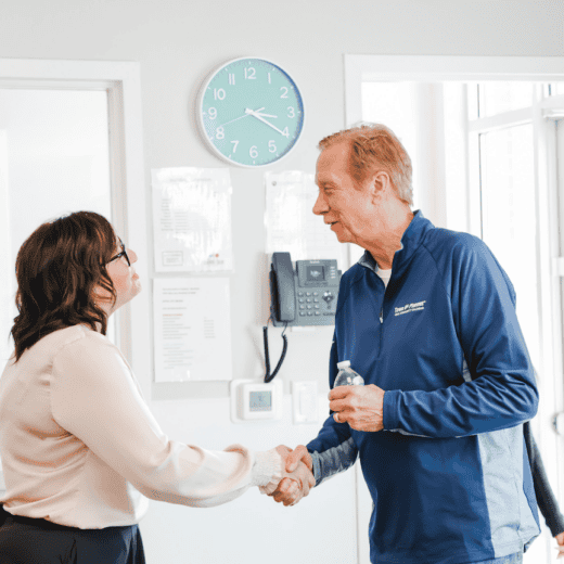 Woman and a man shaking hands and greeting each other.