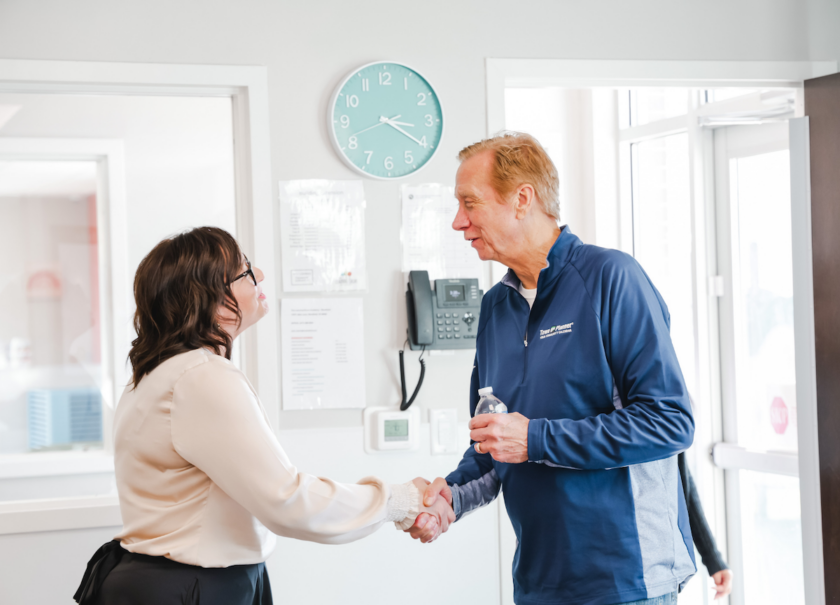Woman and a man shaking hands and greeting each other.