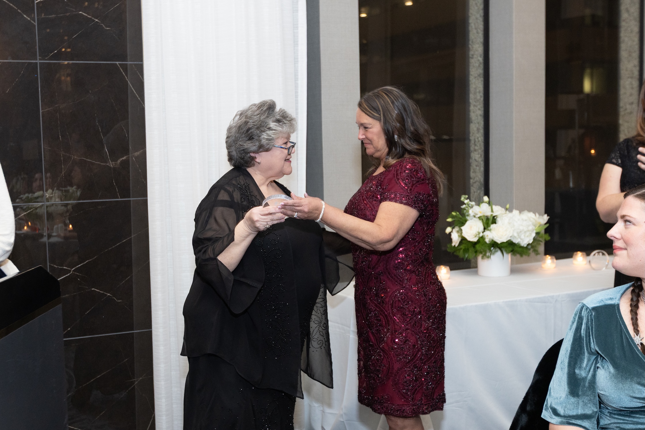 Two woman dressed up at an event talking.